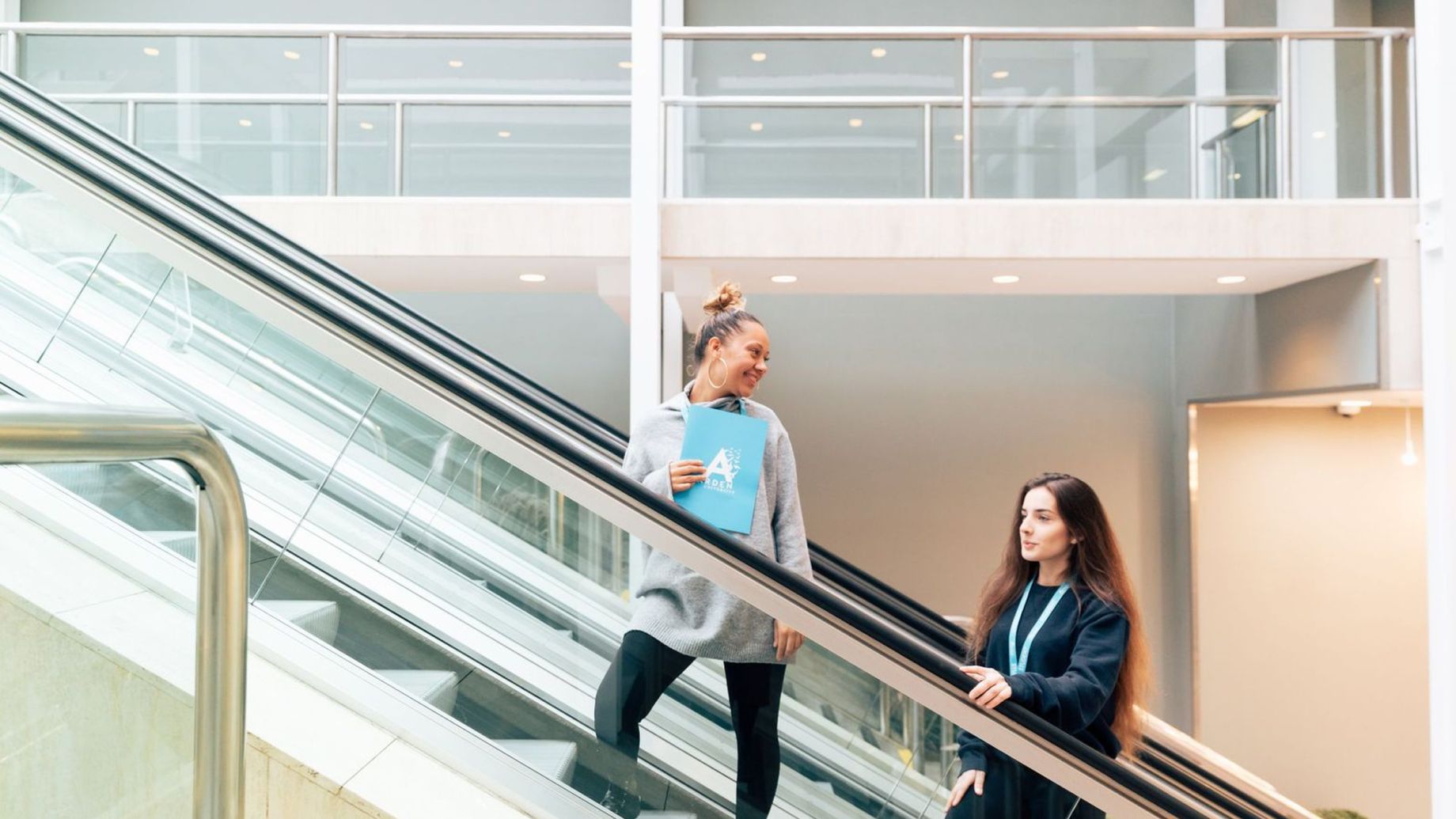 Students smiling on an escalator.