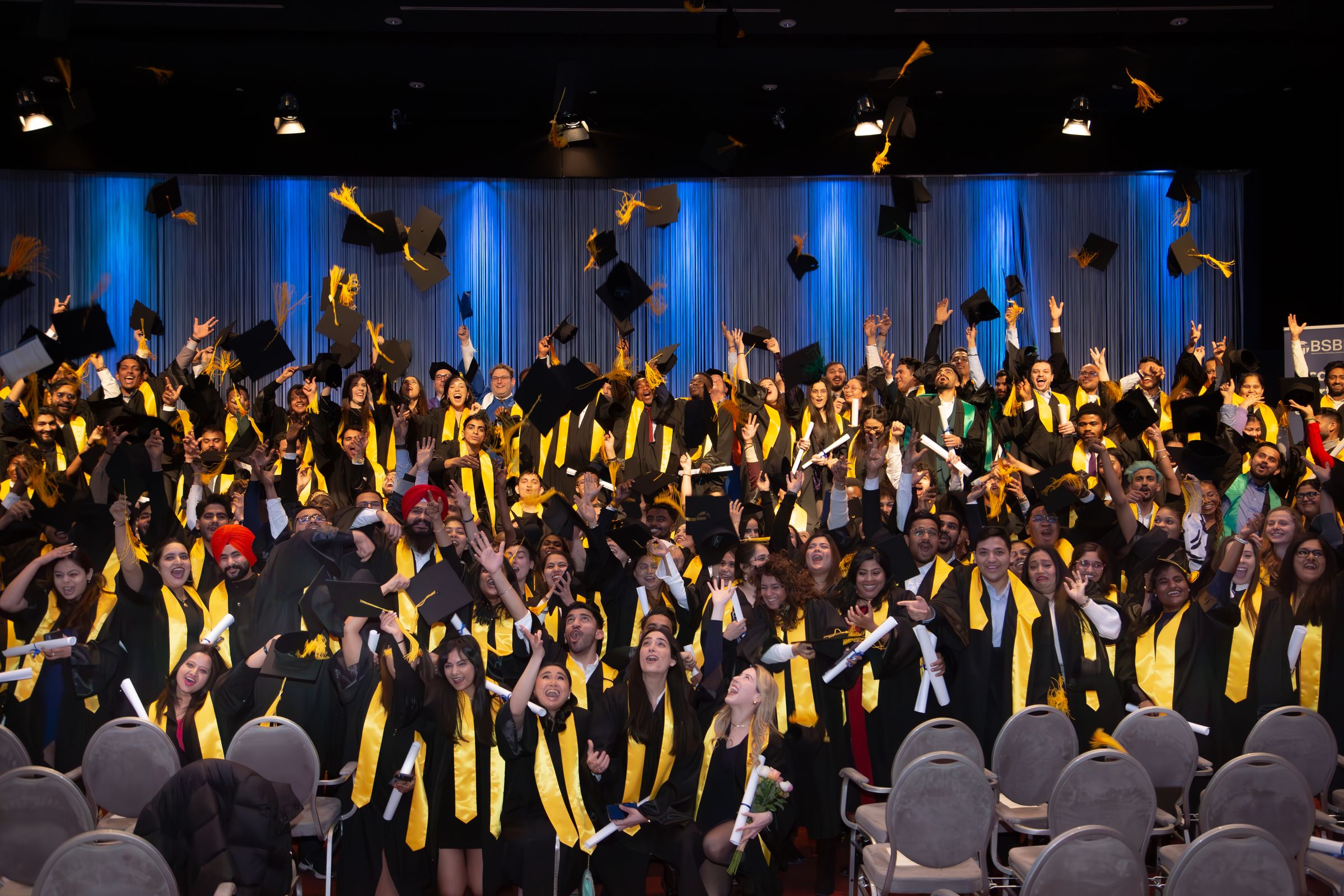 Students celebrate graduation by tossing their caps into the air