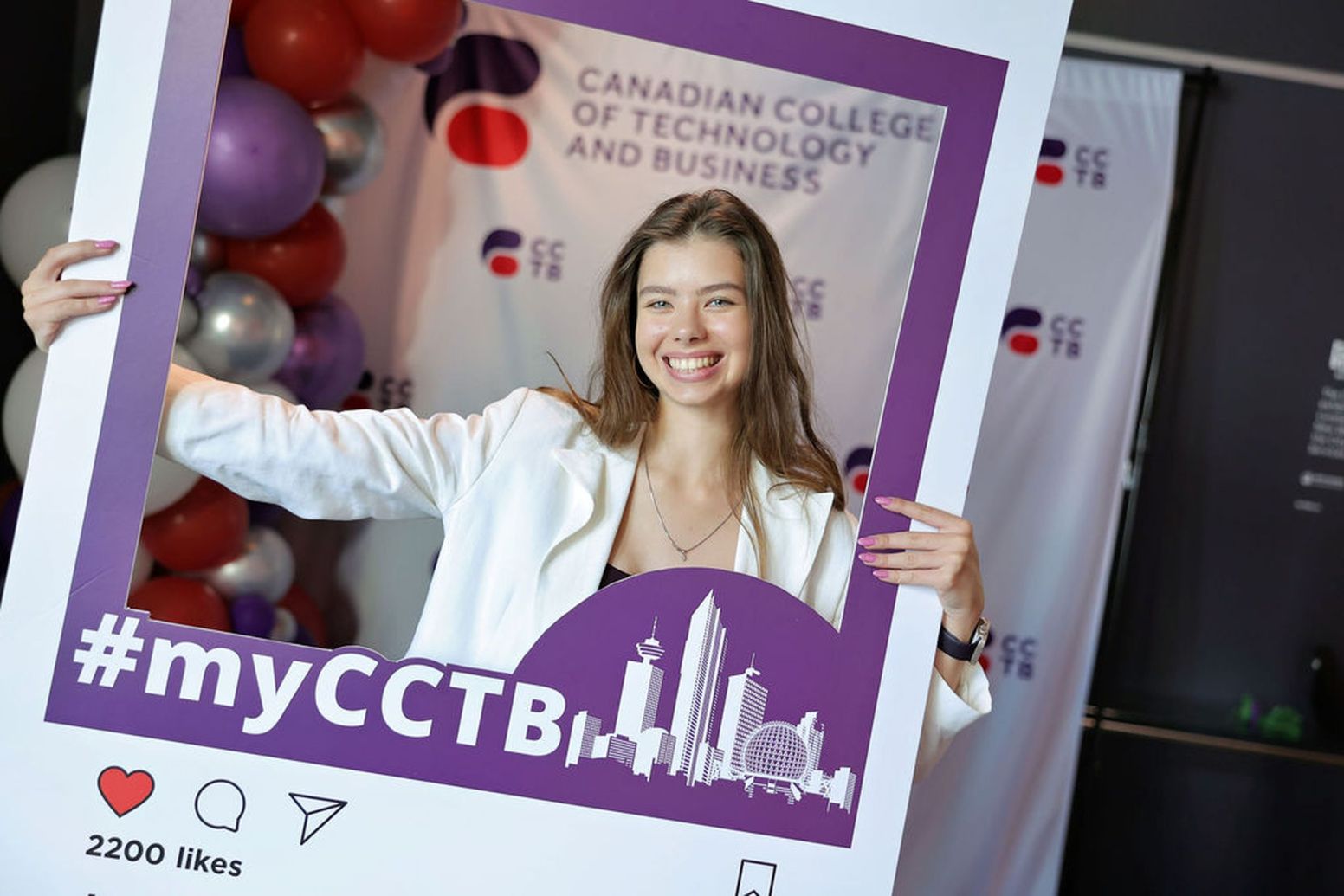 A smiling student holding an Instagram frame whilst posing for a photo.
