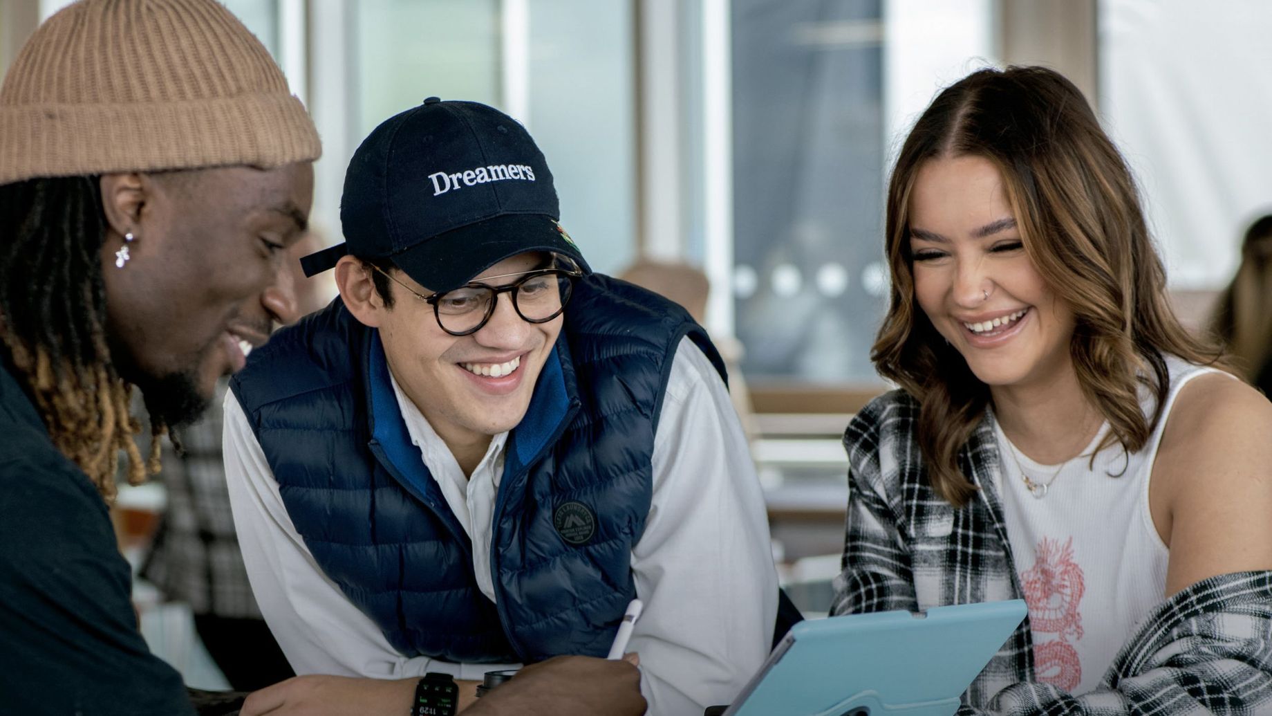 Group of students looking at a tablet screening and smiling.