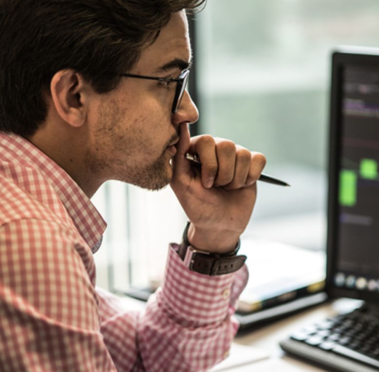 Financial professional reviewing stock trades on desktop screen