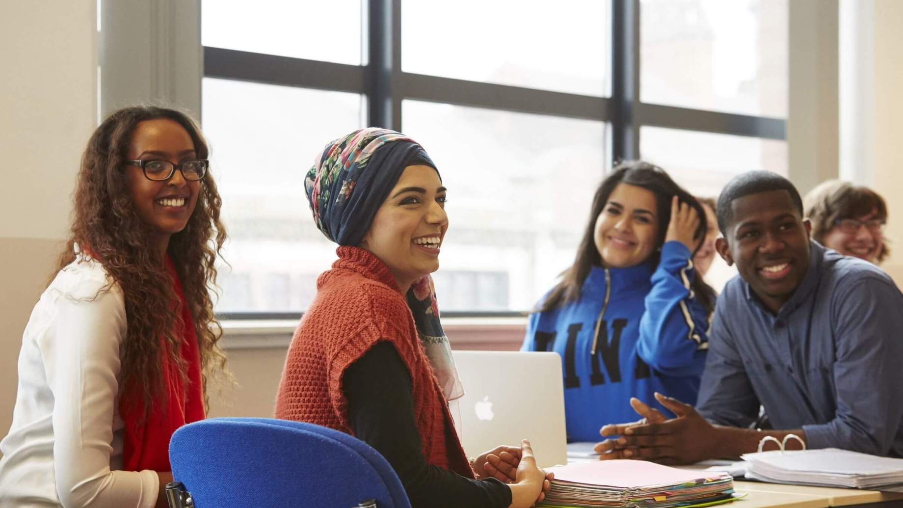 A group of diverse students smiling in a classroom