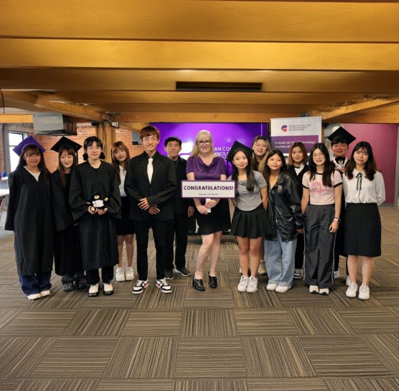 Agroup of students with someone holding a sign saying 'Congratulations'