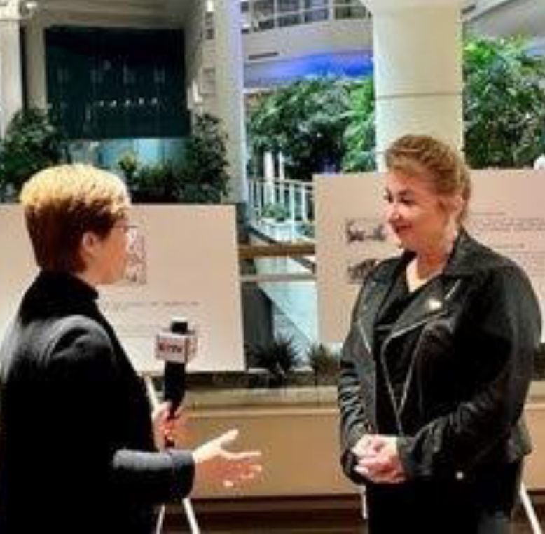 Two women engaged in an interview in an indoor setting with modern architecture and greenery.