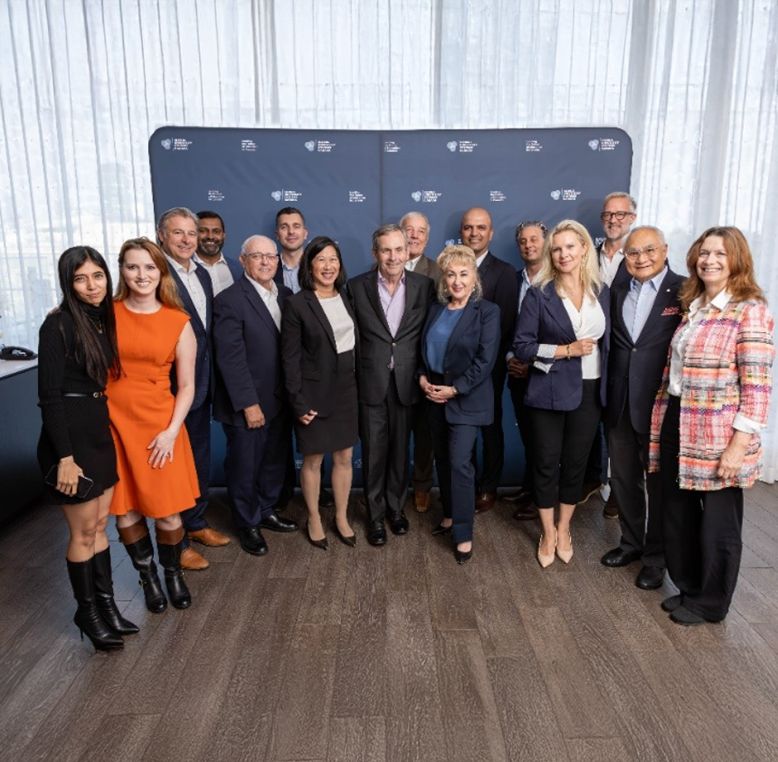 A group of business leaders, health professionals, past government officials and ambassadors smiling.