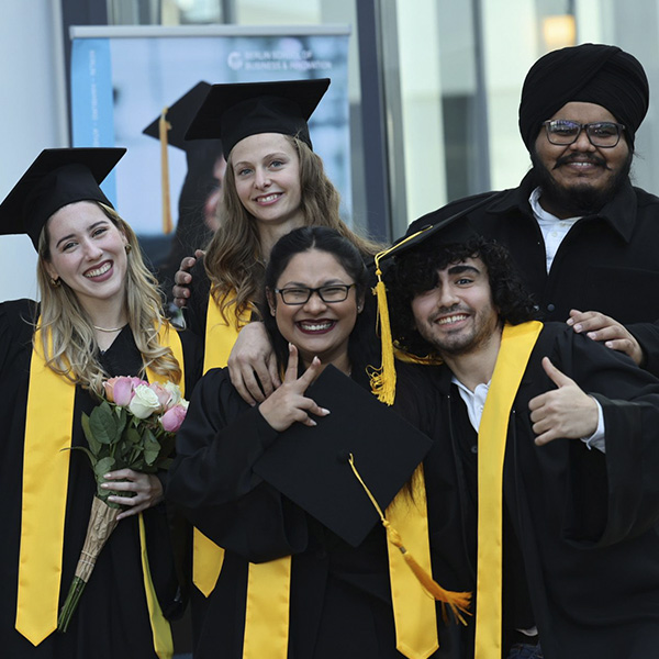 Group of students celebrating their graduation, and smiling at the camera