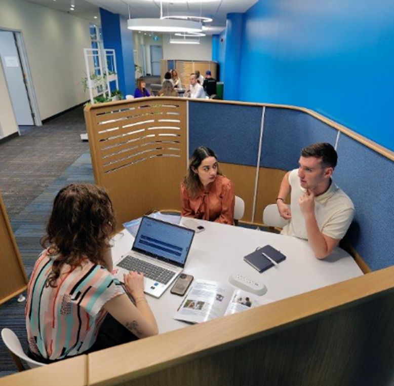 Three students talking at a table.