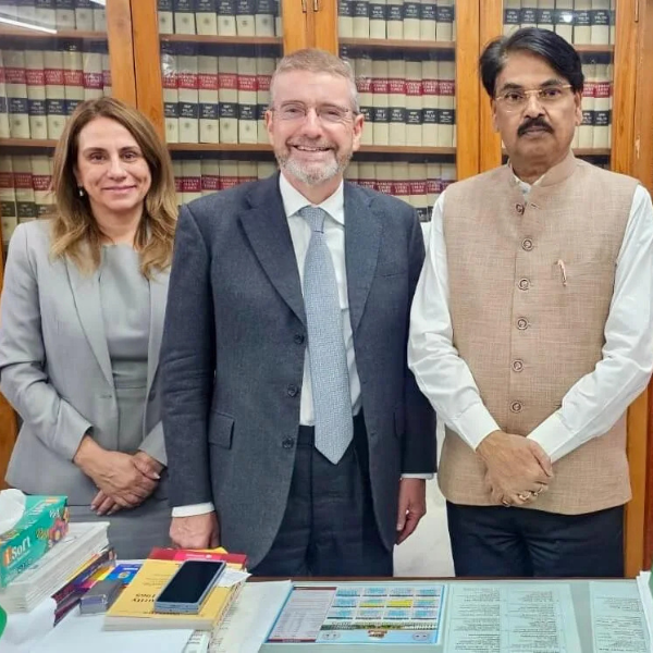 Two ULaw staff members and a Chairman of the Bar Council stand in front of a legal bookshelf.