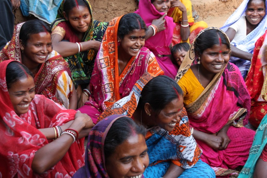 A group of smiling women in colourful saris.