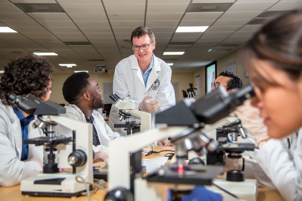 Amedical student talking to a professor, surrounded by medical equipment.