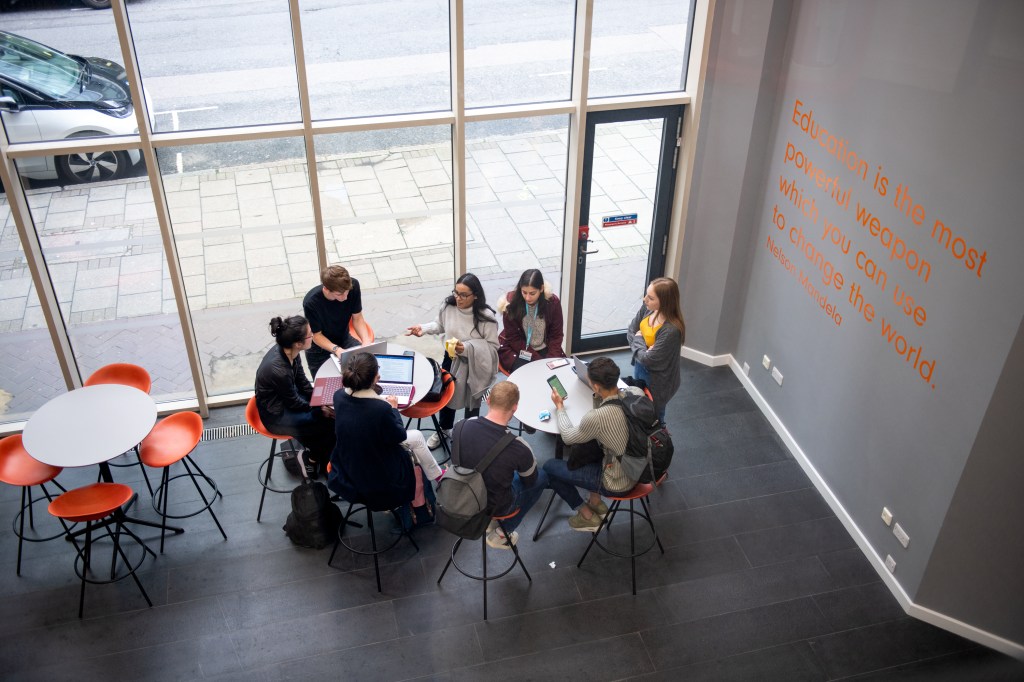 A group of students sitting around a table studying, on campus.