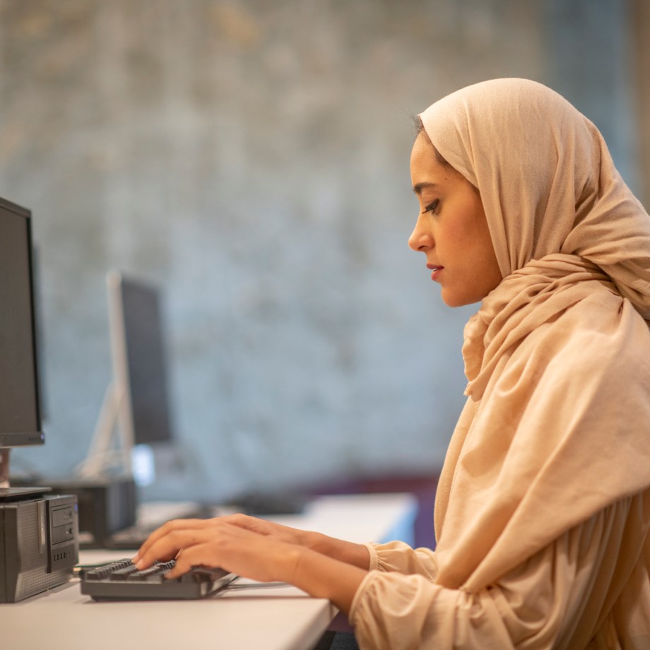 Muslim lady in front of her desktop inside an office space
