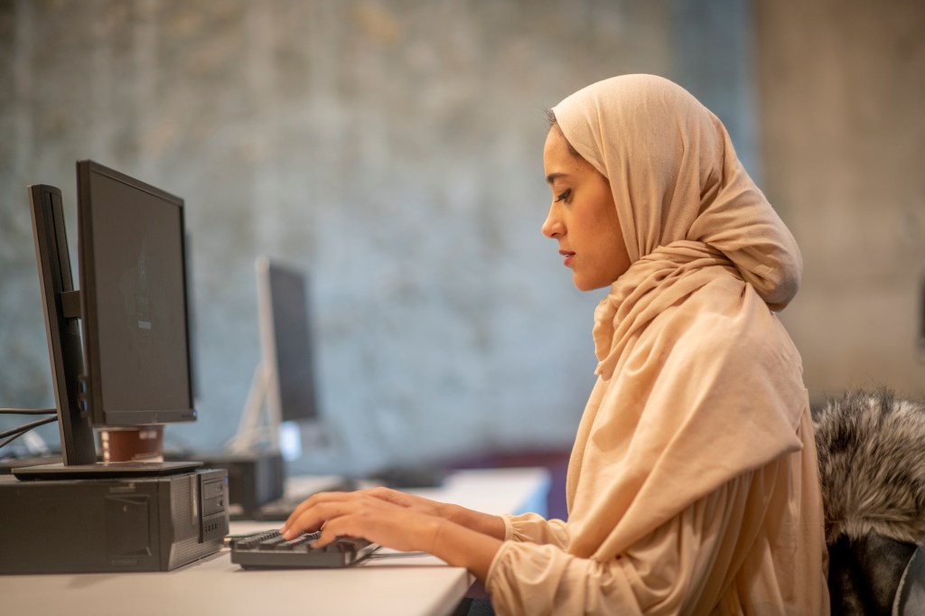 Muslim lady in front of her desktop inside an office space