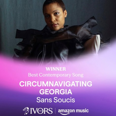 Singer in black outfit with dramatic bow details posing against purple gradient background for Ivor Novello Award announcement.