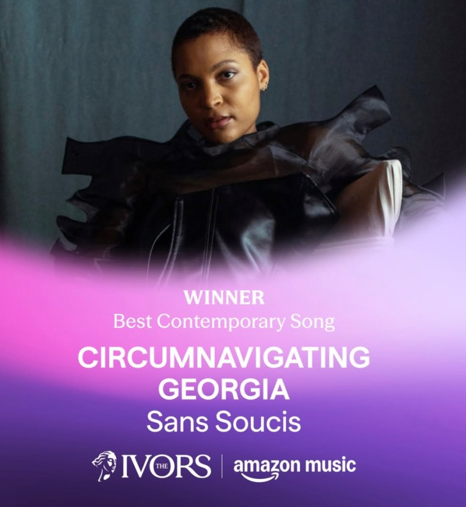 Singer in black outfit with dramatic bow details posing against purple gradient background for Ivor Novello Award announcement.