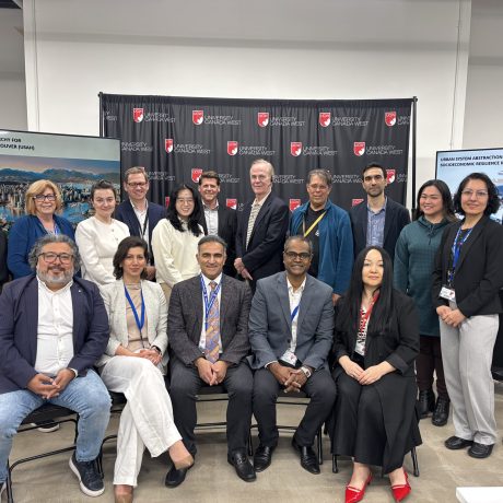 Group photo of conference participants and speakers posed in front of University Canada West backdrop at urban resilience event.