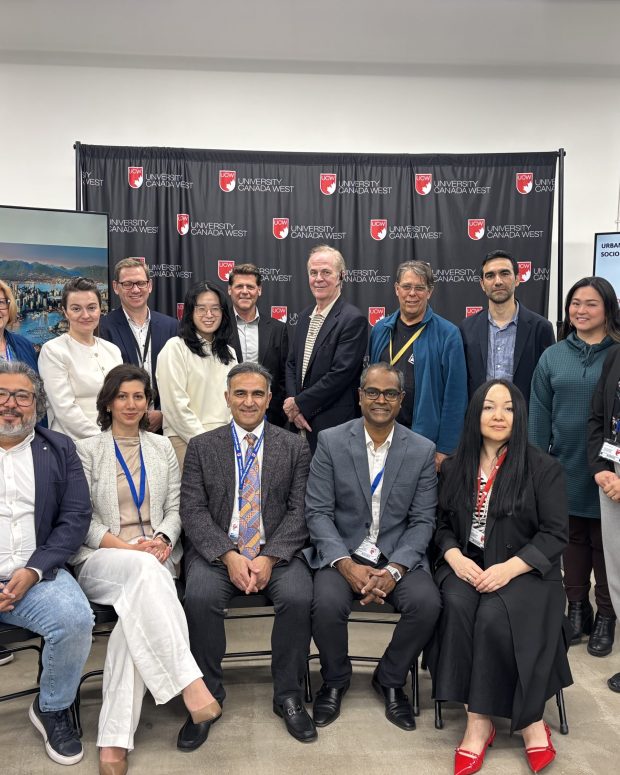 Group photo of conference participants and speakers posed in front of University Canada West backdrop at urban resilience event.