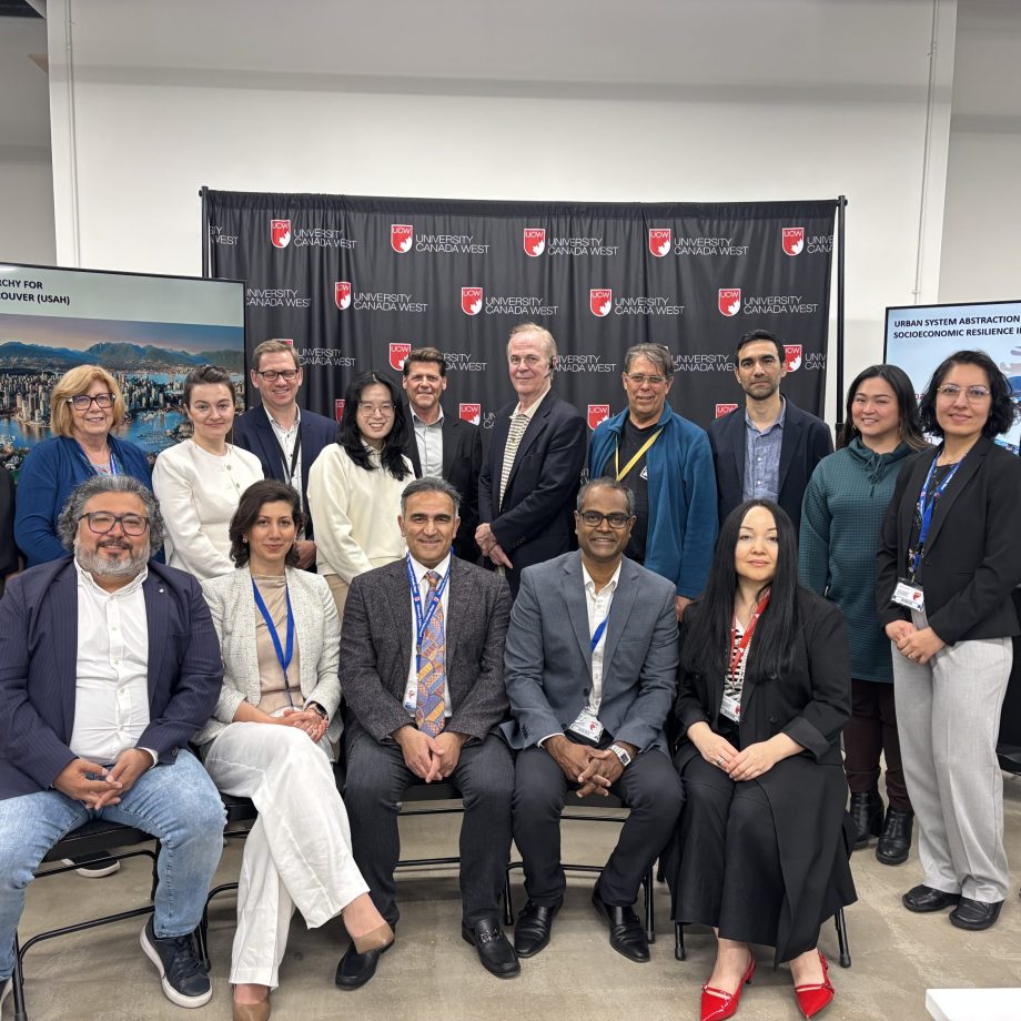 Group photo of conference participants and speakers posed in front of University Canada West backdrop at urban resilience event.