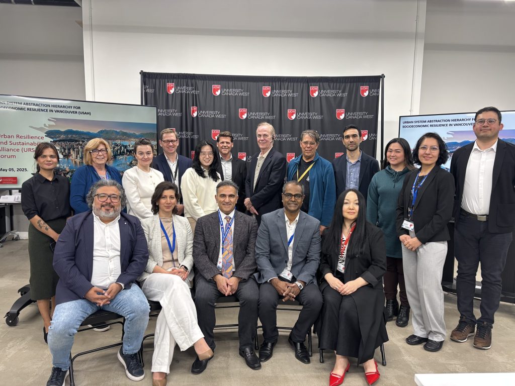 Group photo of conference participants and speakers posed in front of University Canada West backdrop at urban resilience event.
