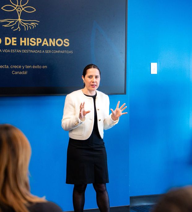 Woman in white blazer presenting to audience at La Red de Hispanos networking event.