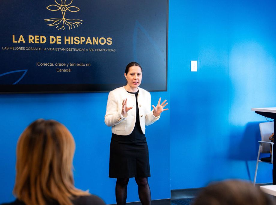 Woman in white blazer presenting to audience at La Red de Hispanos networking event.