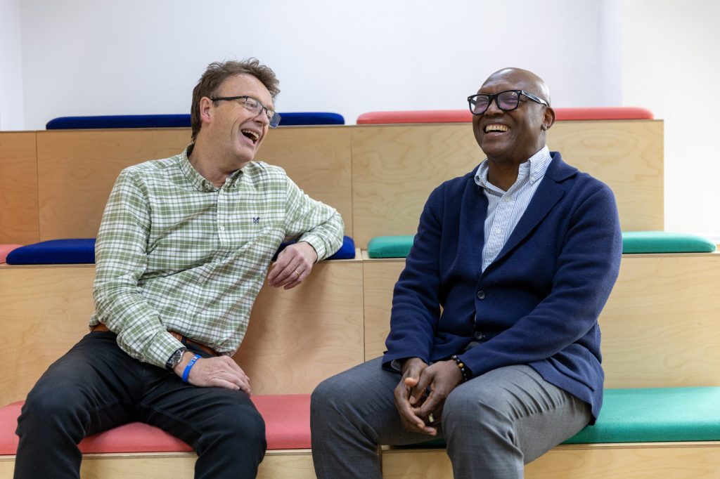 Two men sitting and laughing together on tiered benches.