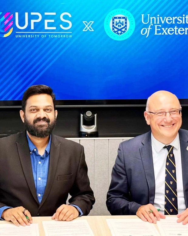 Two men signing a partnership agreement between UPES and University of Exeter.