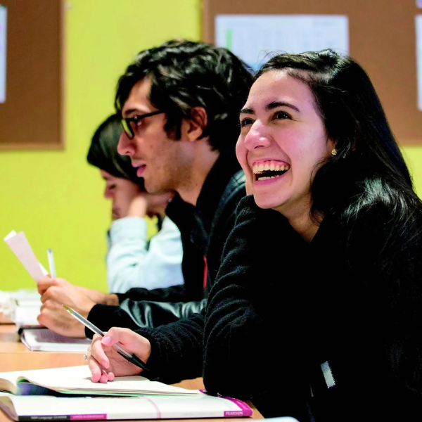 Students sitting in a classroom writing and smiling.