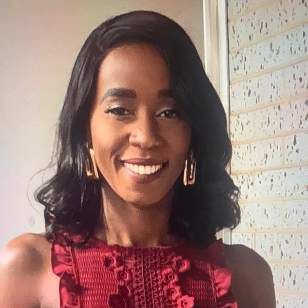 Sheryll Kintu smiling, wearing a red sleeveless top and gold earrings
