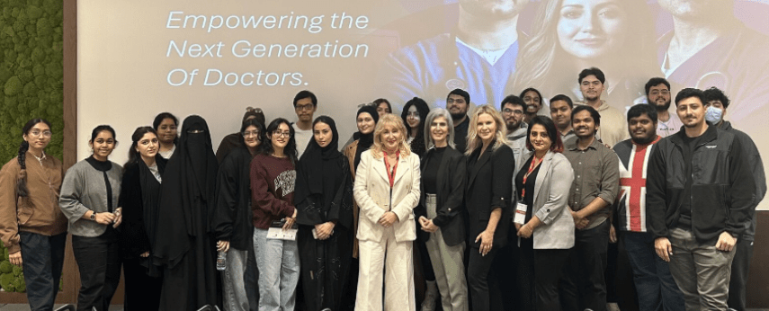 Group photo of students and faculty standing together in front of a presentation screen that reads “Empowering the Next Generation of Doctors.”