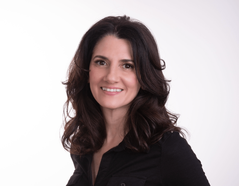 Woman with shoulder-length dark hair wearing a black shirt against a plain light background