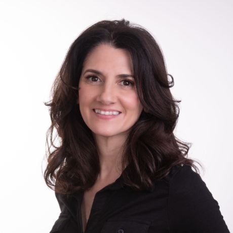 Woman with shoulder-length dark hair wearing a black shirt against a plain light background