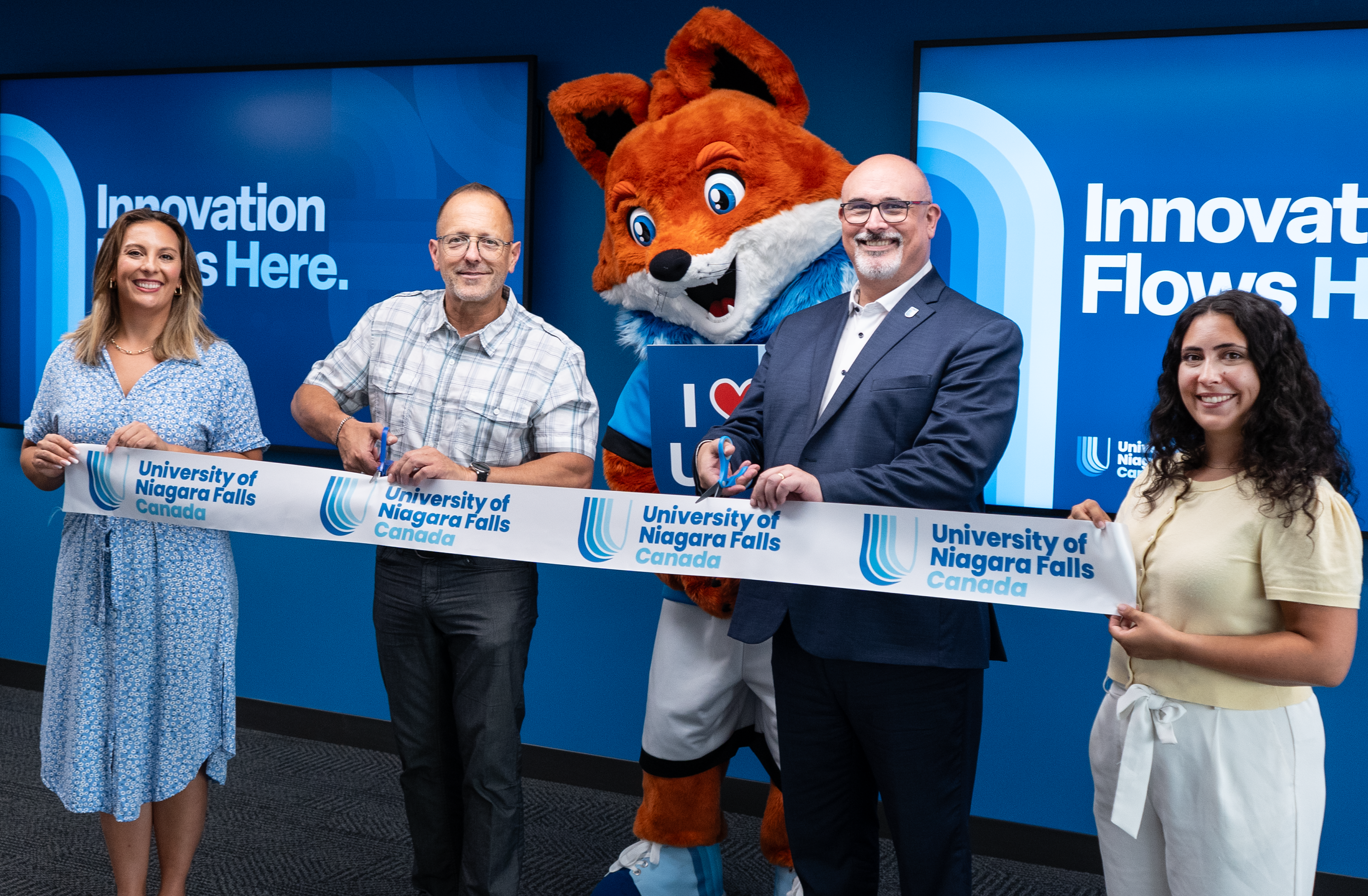 University of Niagara Falls Canada ribbon-cutting ceremony with staff and mascot.