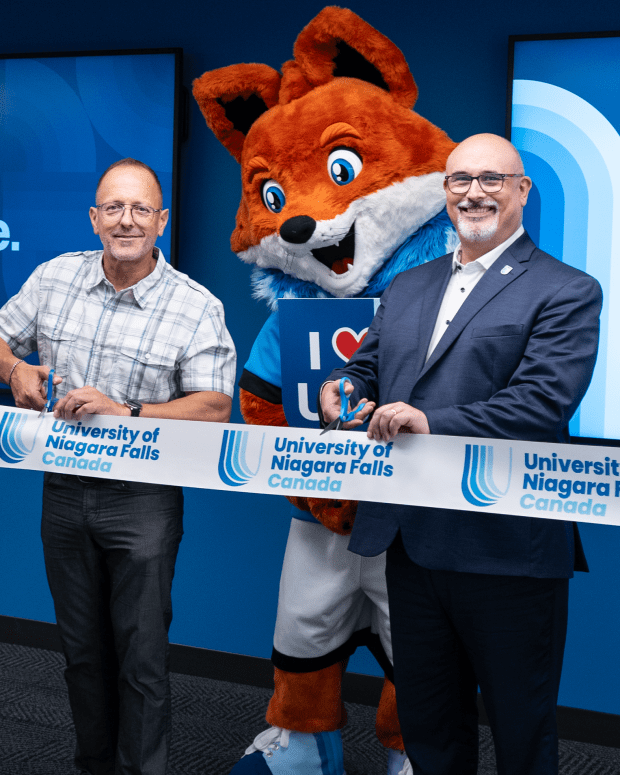 University of Niagara Falls Canada ribbon-cutting ceremony with staff and mascot.