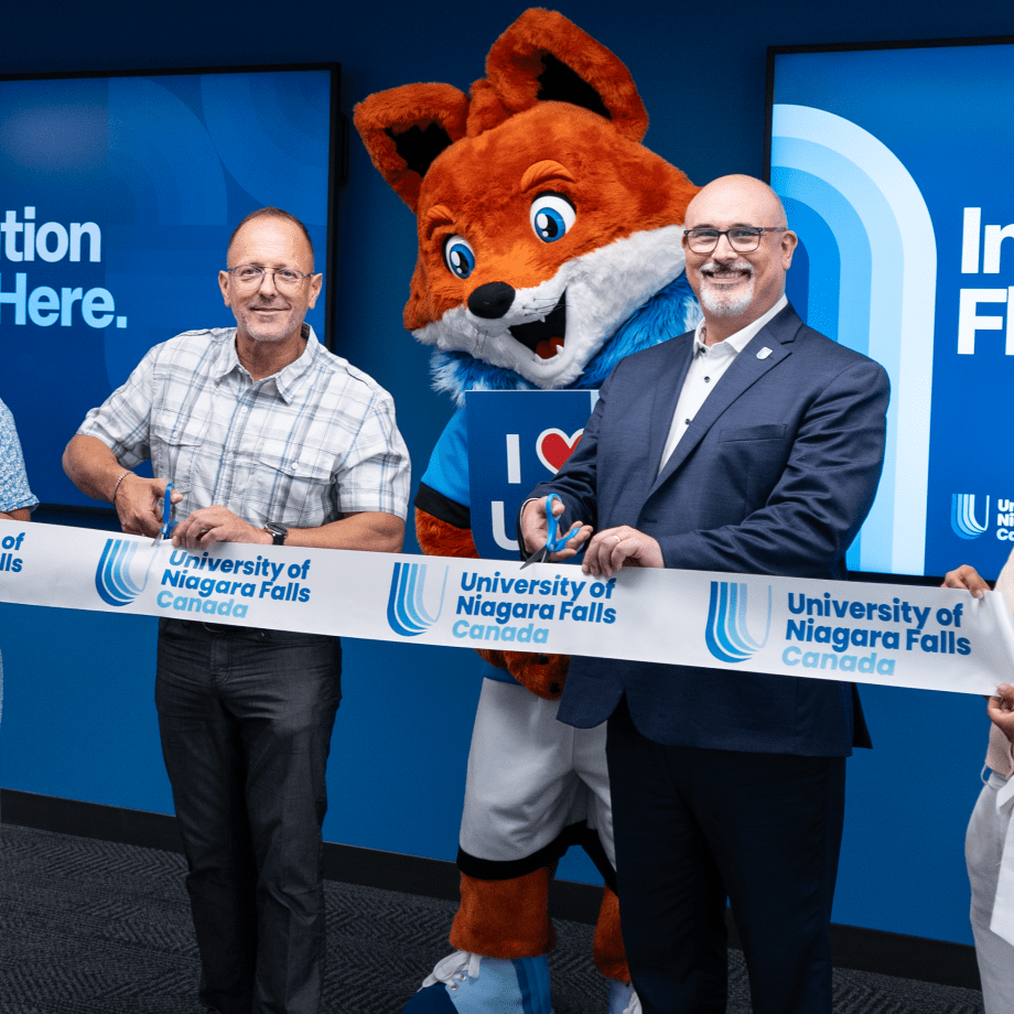 University of Niagara Falls Canada ribbon-cutting ceremony with staff and mascot.